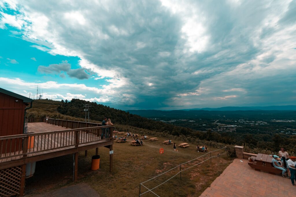 brown wooden fenced  deck near body of water under white clouds and blue sky during daytime