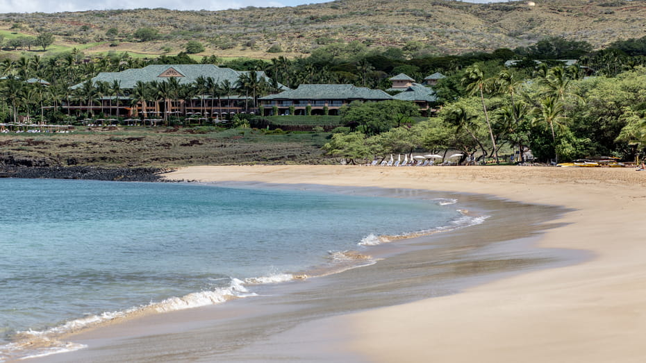 A deserted Hulopoe Beach, rolling green hills in the background